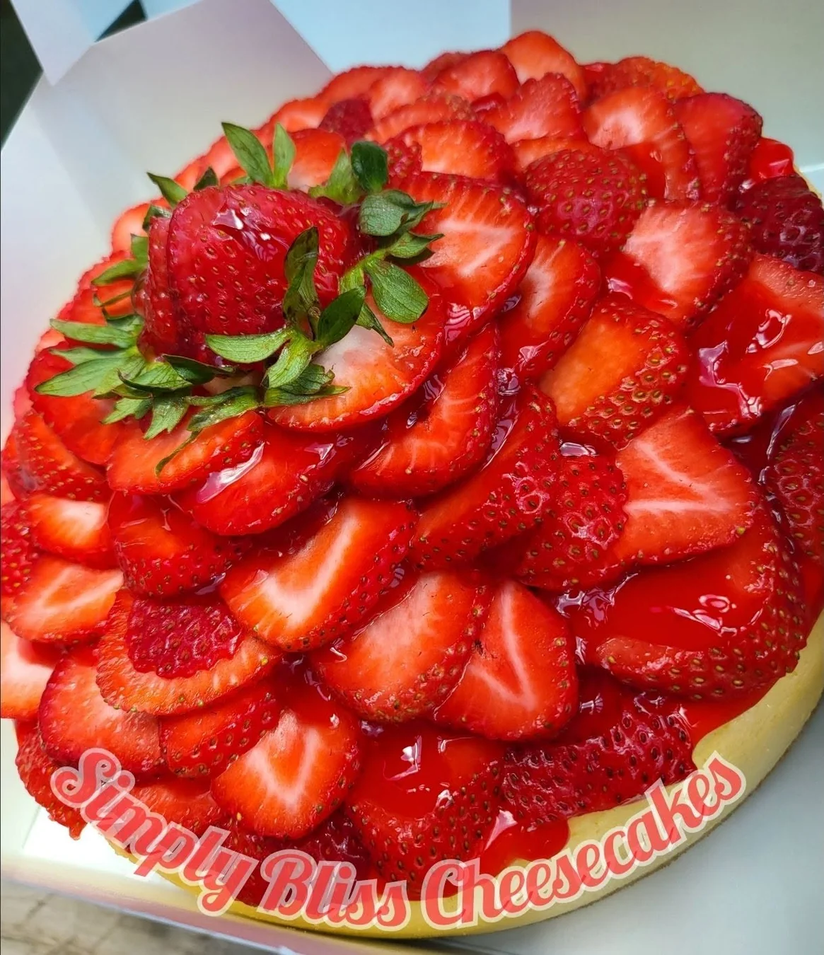 Whole cheesecake generously topped with fresh strawberries