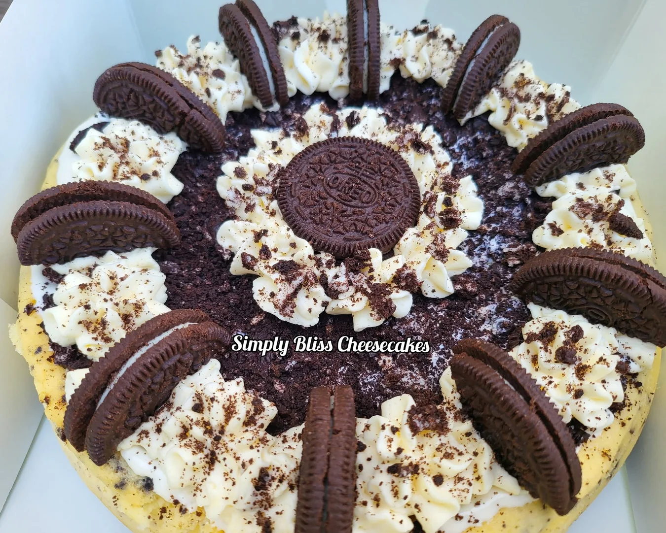Whole cheesecake lavishly decorated with chocolate sandwich cookies and piped cream